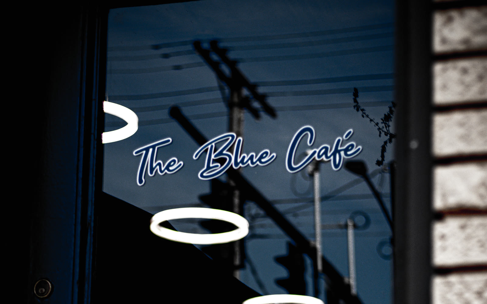 The Blue Café name and glowing ring lights reflected in the front door.