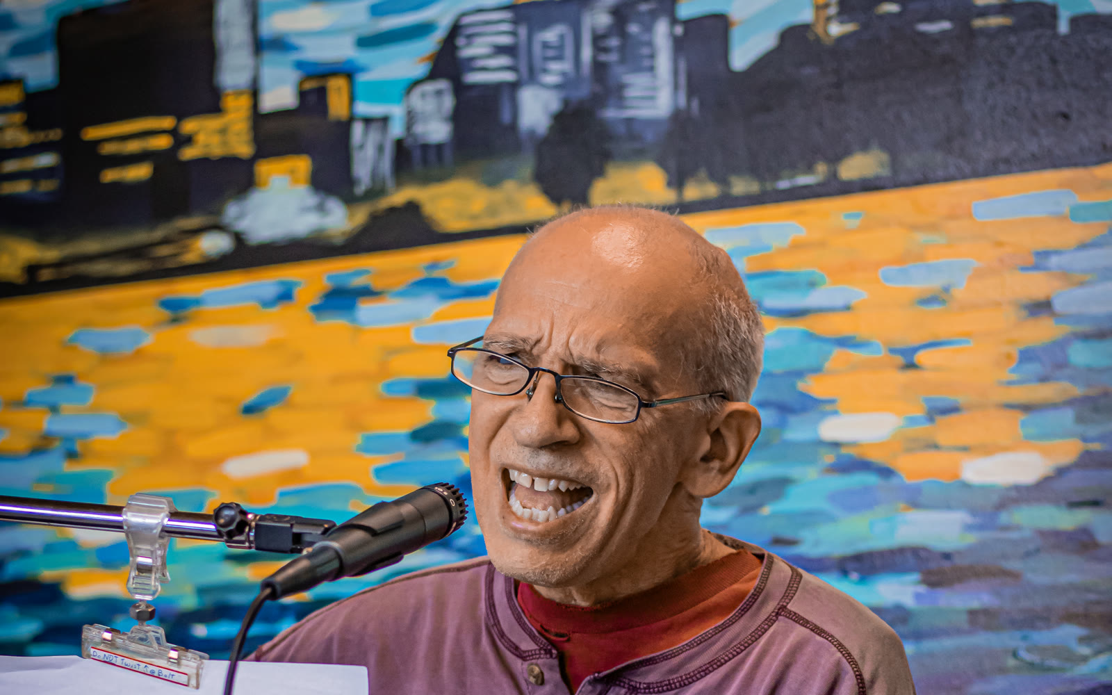 A guitarist sings in front of the colorful wall mural inside the Blue Cafe.